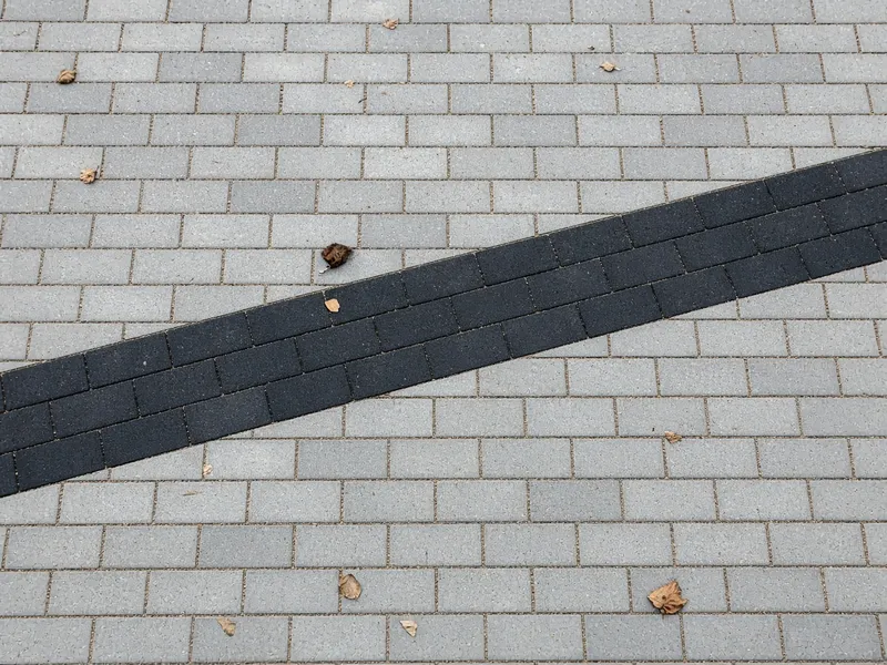 Grå belegningsstein med et diagonalt bånd i svart